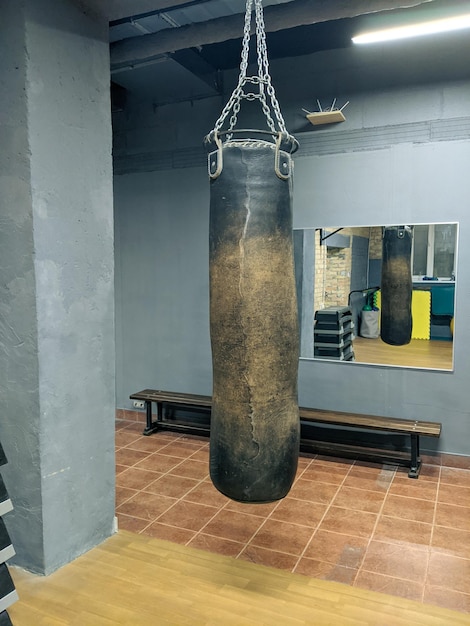 old beaten punching bag in boxing club gym