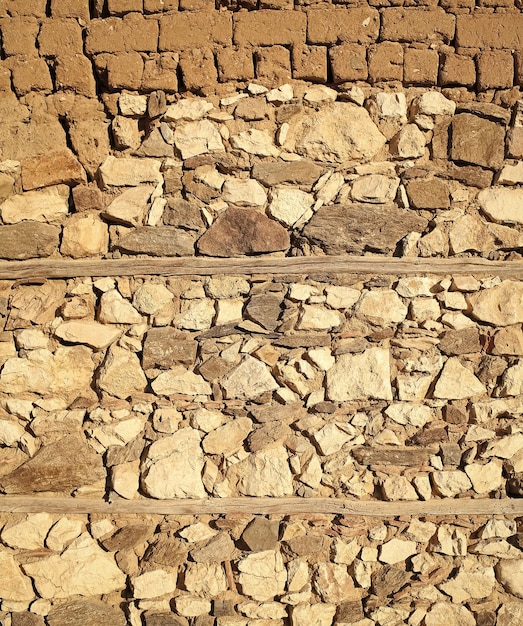 古いベージュの石の壁の背景のテクスチャをクローズアップ石とレンガで作られた古代の壁テクスチャと背景の概念古代の建物の建築の一部