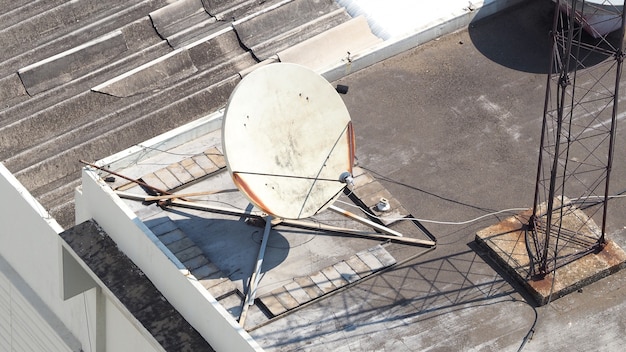 Old big telecommunication satellite dish on roof top of building.