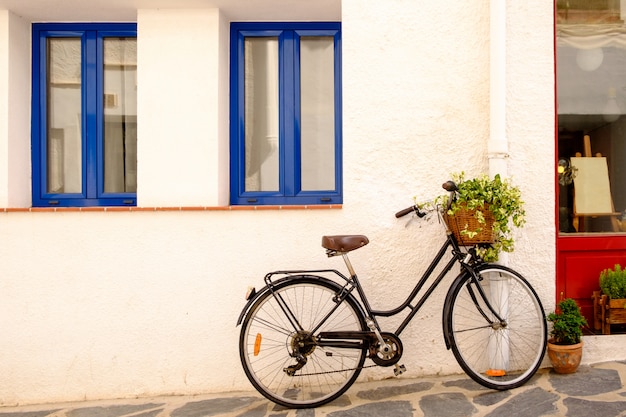 Old black bicycle against a white wall