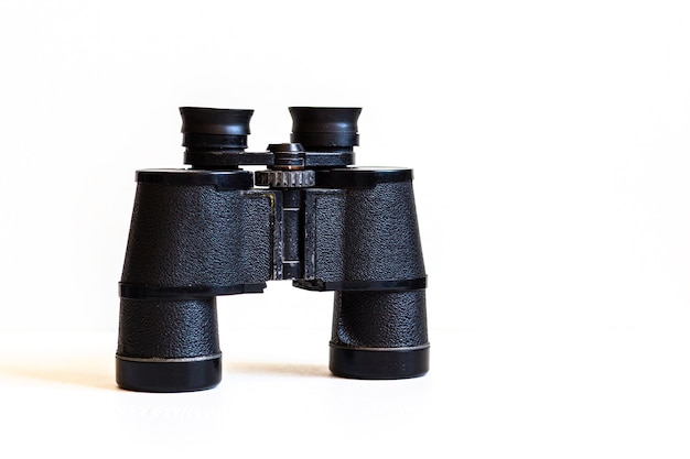 Old black binoculars close up on white background