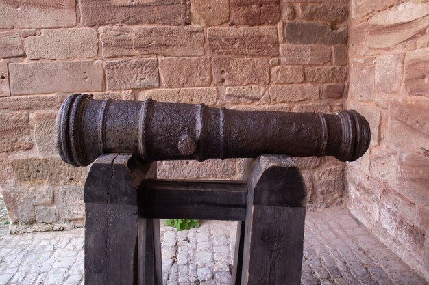 Old black cannon pointing through an opening in a castle rampart with the sea in the background