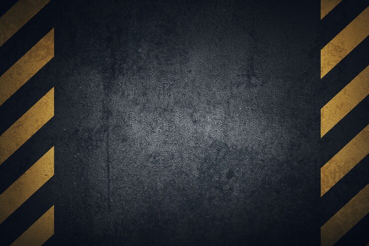 Photo old black grungy metal plate surface with yellow warning stripes.