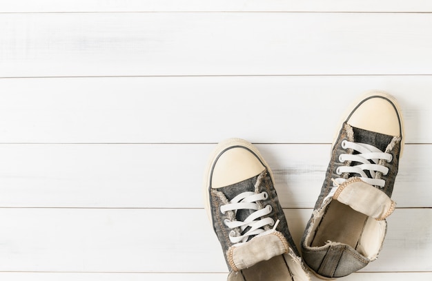 Old black sneakers on white wood background