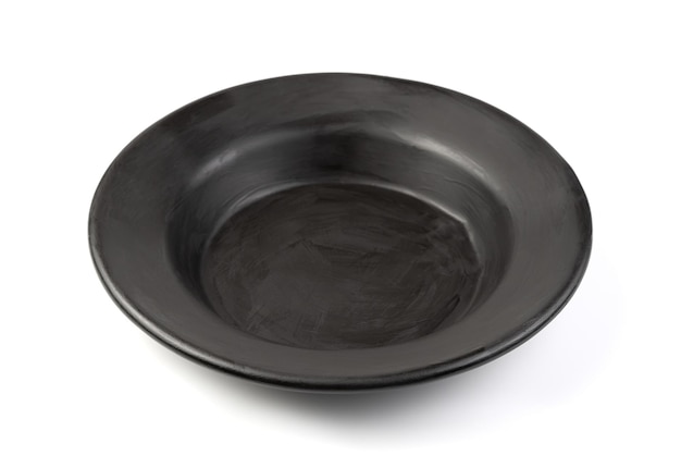 Старая черная суповая тарелка на белом фоне. Стилизованная посуда. Вид сбоку.