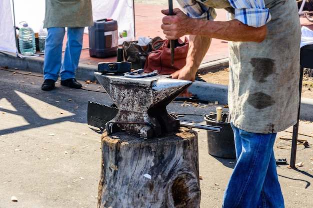 Old blacksmith forging horseshoe on the anvil