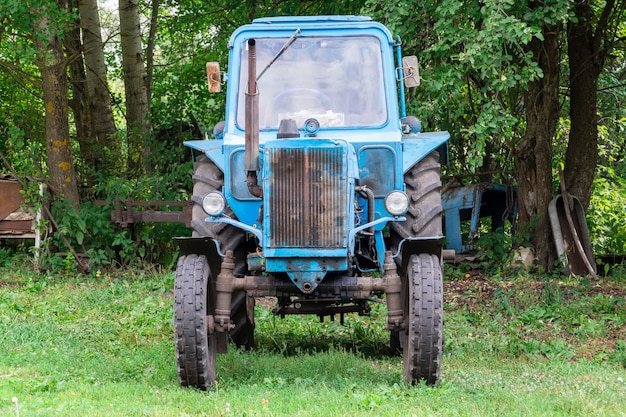 Un vecchio trattore blu è in piedi sull'erba dopo il lavoro