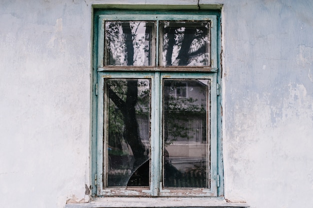 Old blue wooden window with beaten glass 