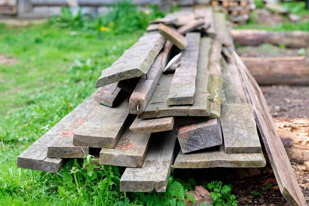 Old boards are lying on the green grass in the yard