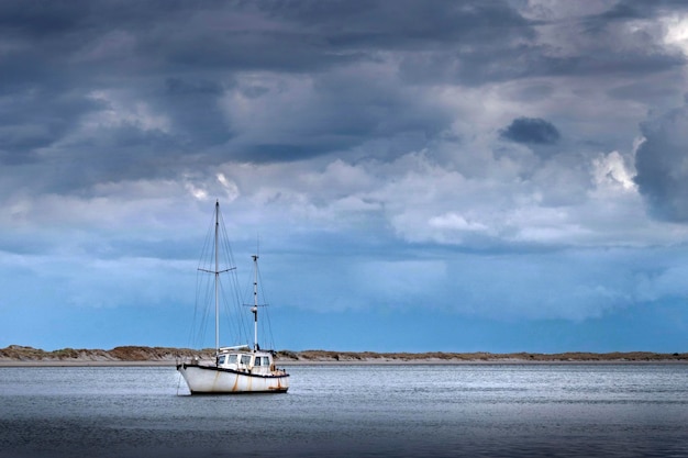 Foto vecchia barca in mare a mangawhai si dirige verso la costa della nuova zelanda e le nuvole