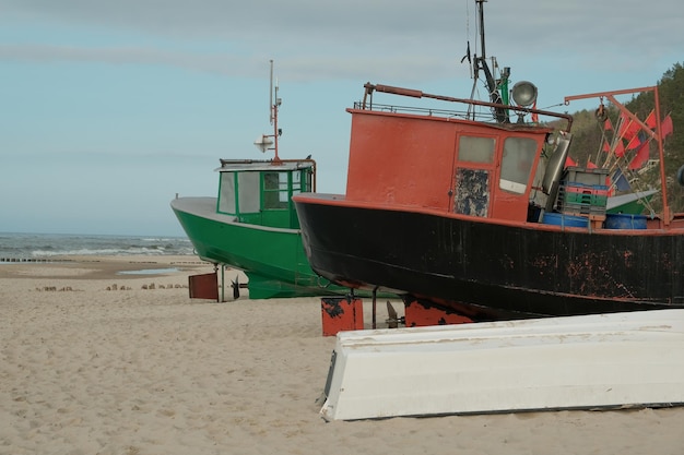 Old boats stand on the beach by the seaAn old peeling fishing boat stands on the shore A fishing net hangs on a boat