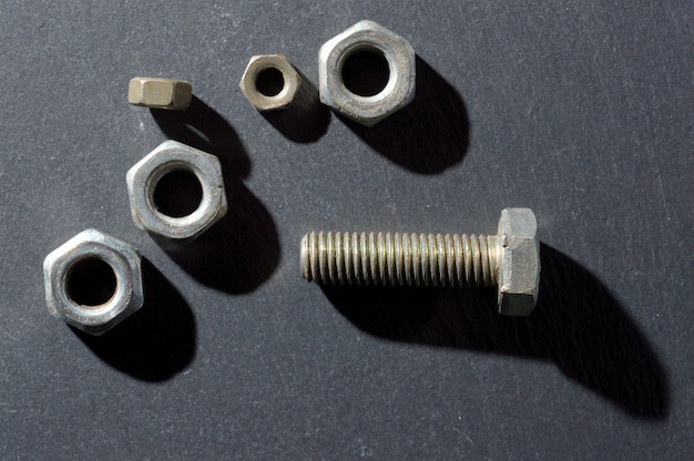 Old bolts and nuts on a dark background.