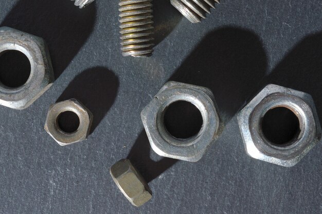 Old bolts and nuts on a dark table. Top view.