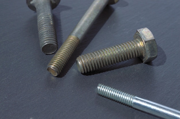 Old bolts and nuts on a dark table.