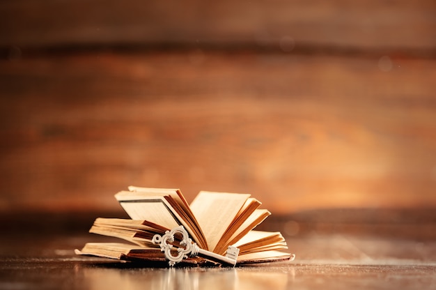 Old book and key on wooden table