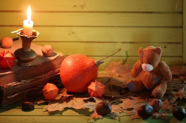 Old book pumpkin and candle on wooden table