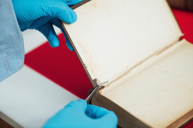 Old book restoration conservator repairing antique book in restoration laboratory