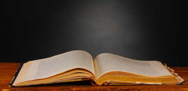 Old book on wooden table on gray background