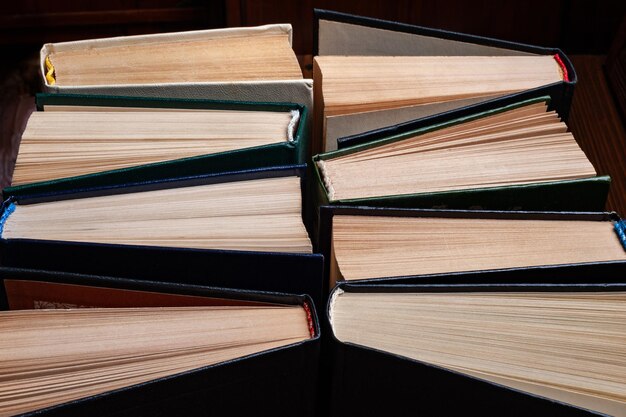 Old books Closeup group of old used open hardback books in dust on dark wooden background