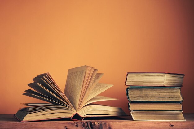 Old books on a old wooden table Beautiful orange wall background