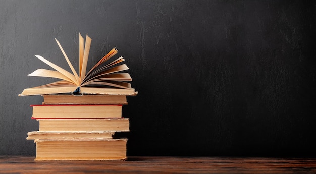 Old books on wooden table and blackboard