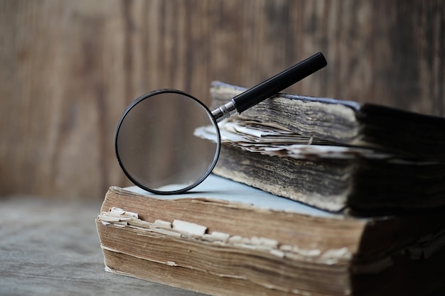 Old books on a wooden table and glass magnifier