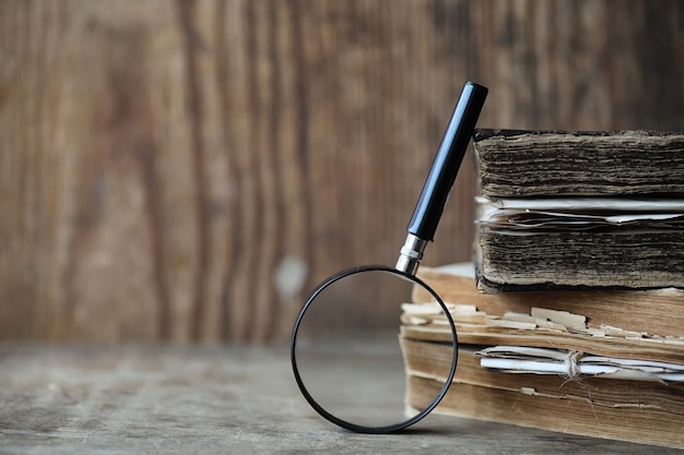 Photo old books on a wooden table and glass magnifier