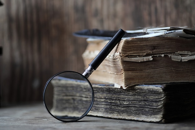 Old books on a wooden table and glass magnifier