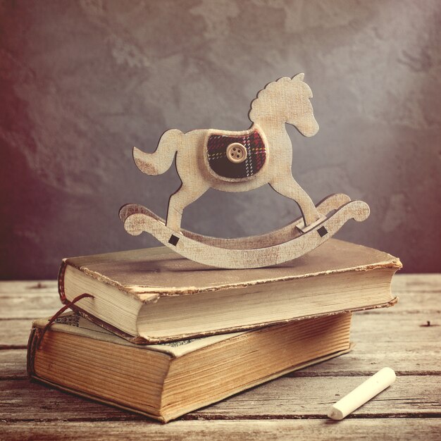 Old books and wooden toy horse