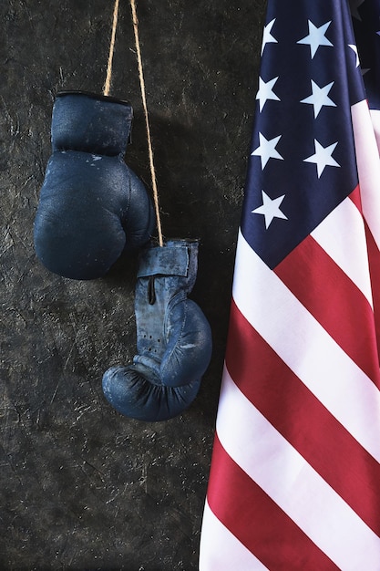 Photo old boxing gloves hang on the wall next to the flag of the united states of america.