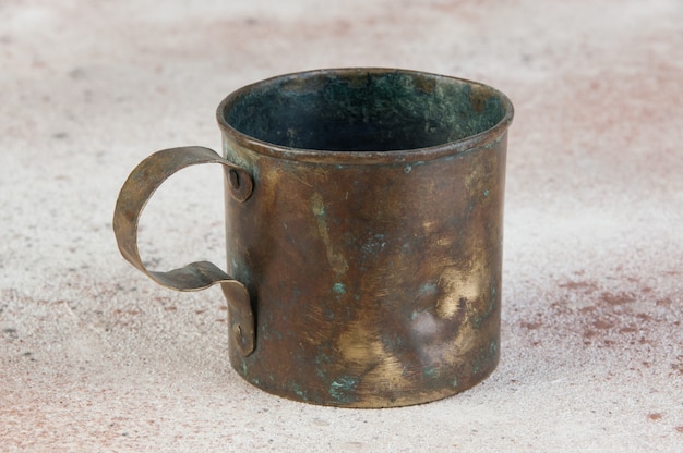 Photo old brass mug with handle on concrete