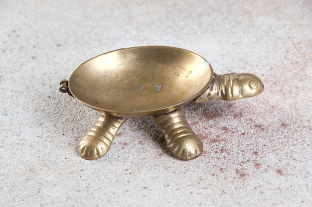 Old brass turtle ashtray on concrete background. Copy space and photography props.