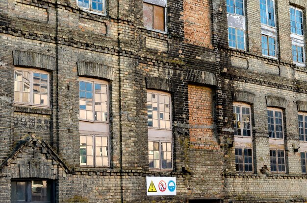 Photo old brick building nonresidential destroyed structure house with broken windows repair of the old building warning signs on the facade bad living conditions for people