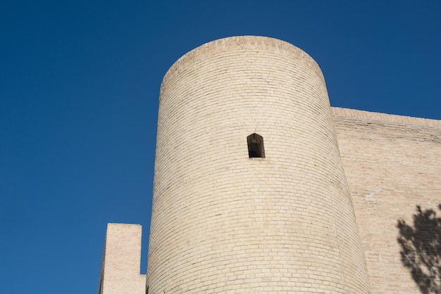 Старое кирпичное здание с башней. Древние постройки средневековой Азии. Бухара, Узбекистан