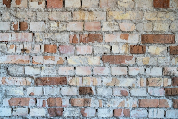 An old brick wall in an uninhabited building a destroyed house\
after a tornado or cataclysm poorquality plaster falls off from a\
brick wall