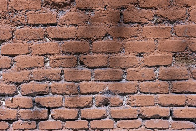 An old brick wall with deformities painted in a pale pink color
