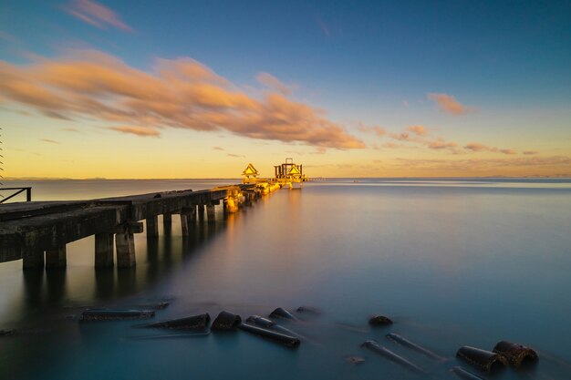 Photo the old bridge into the sea on the beach at sunrise