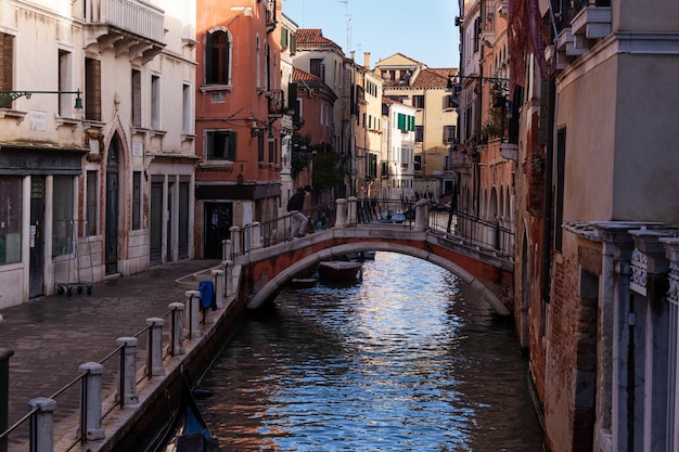 The old bridge made with red bricks on the typical canal in Venice