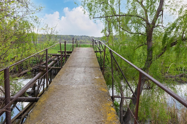 An old bridge over a river in the village Concrete and steel bridge green trees spring time