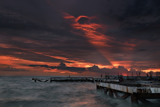 The old bridge in to the sea with sunset sky