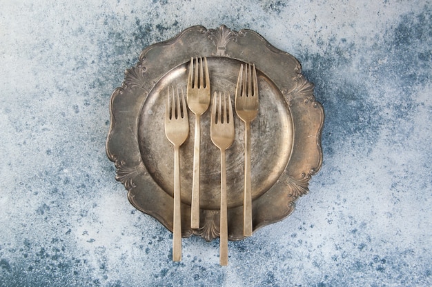 Old bronze forks on vintage dish