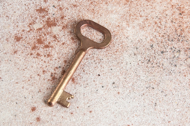 Old bronze key on concrete background.