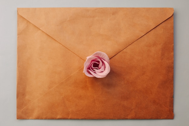 An old brown envelop with pink rose flower on a blue background