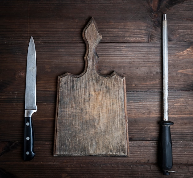  old brown wooden cutting board and knife with sharpening