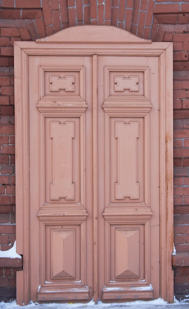 An old brown wooden door on a brick wall