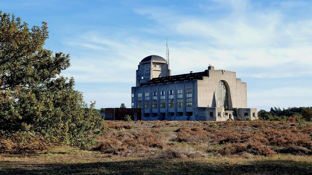 Foto vecchio edificio dagli alberi sul campo contro il cielo