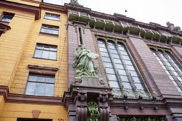 女性アーティストと子供の緑の彫像と黄色とピンクのレンガで作られた古い建物の壁-サンクトペテルブルク、ロシア、2020年10月