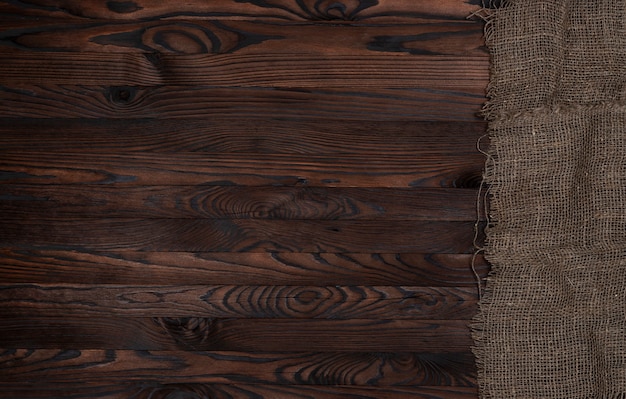 Старая салфетка ткани мешковины на коричневой деревянной предпосылке, взгляд сверху