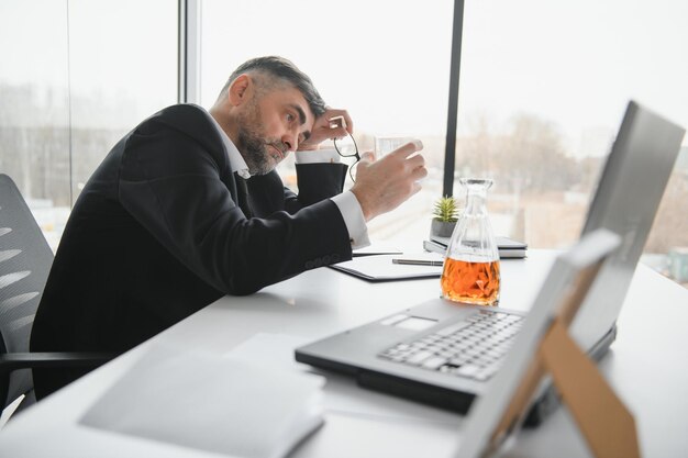 Old businessman drinking from stress