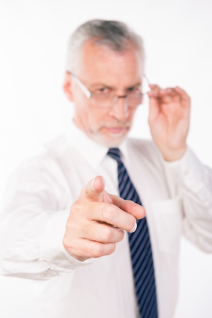 Old businessman holding his glasses and pointing straight, focus on hand